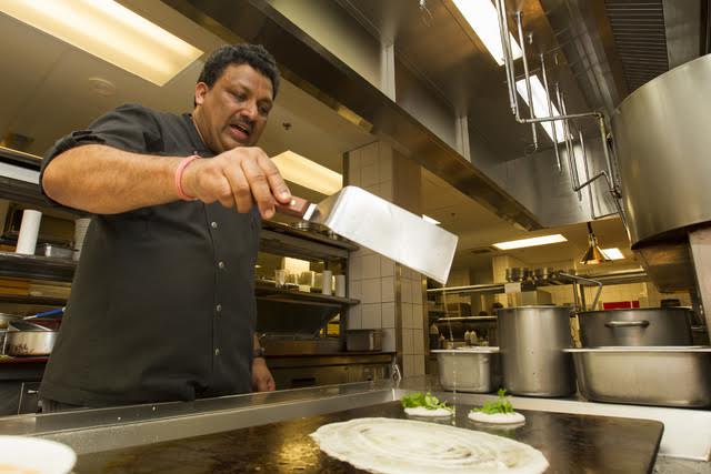 CINDY ELLEN RUSSELL / CRUSSELL@STARADVERTISER.COM Halekulani executive chef Vikram Garg adds batter to the grill to make rice and lentil pancakes called uttapam, as well as a larger crepe made from the same batter. Various fresh toppings give uttapam a pizzalike look.
